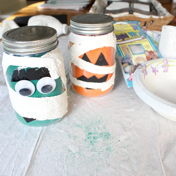 Create adorable mummy mason jar candleholders for Halloween with Rigid Wrap plaster cloth and Scenic Sand colored sand!